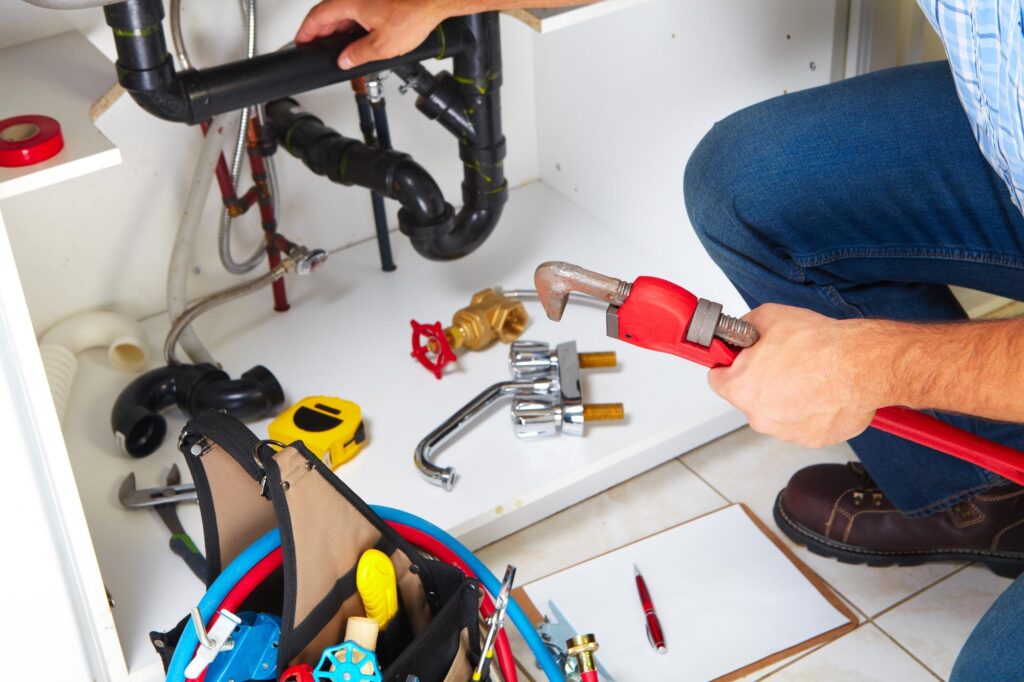 Find a reputable plumber. Plumber with Plumbing tools on the kitchen. Renovation.