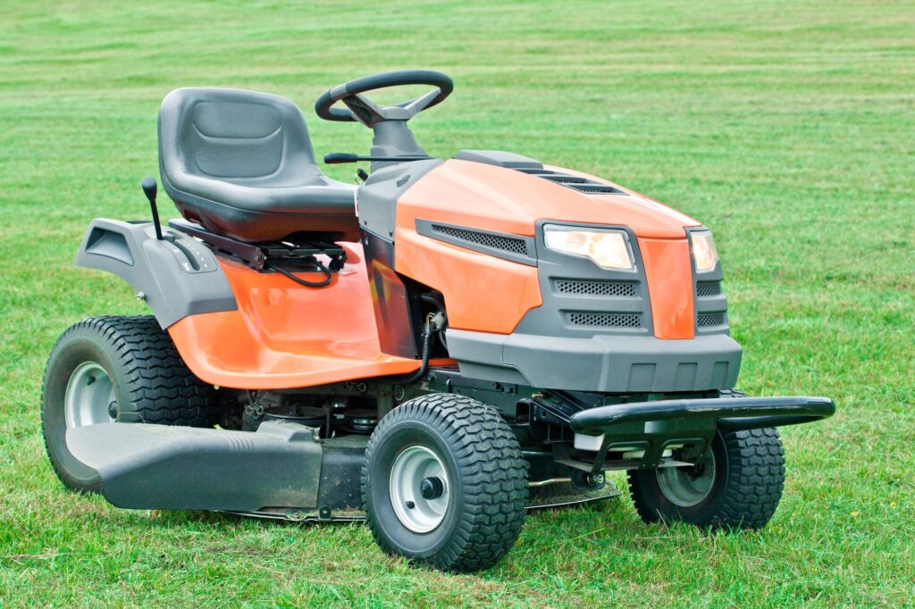 a red riding lawn mower situated on green grass with lights on