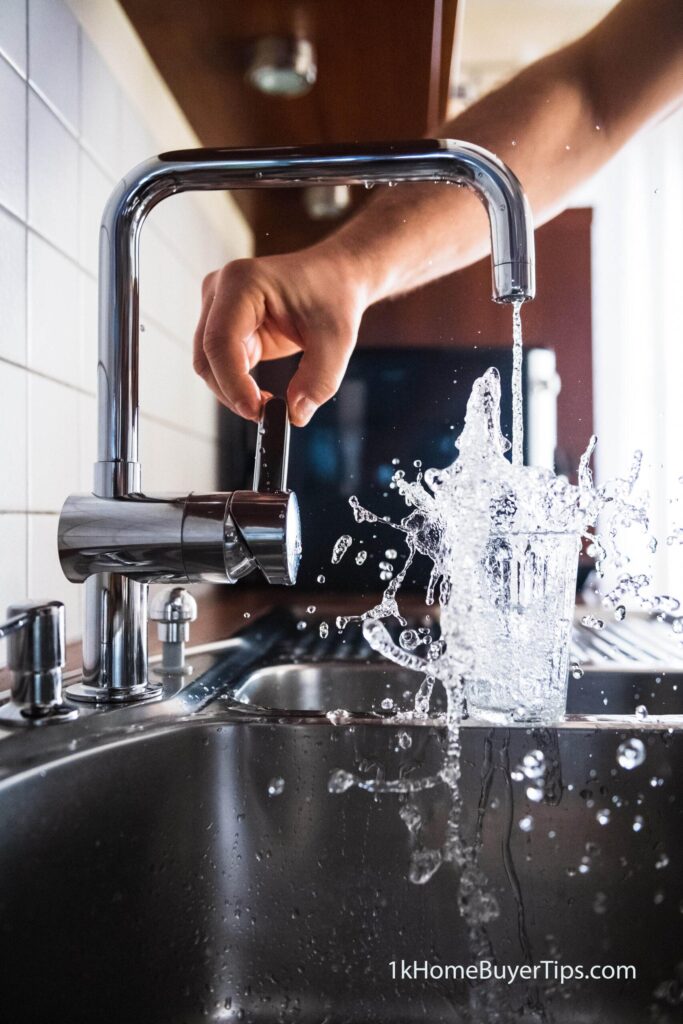 water coming out of a faucet with a hand on the lever. - best home plumbers