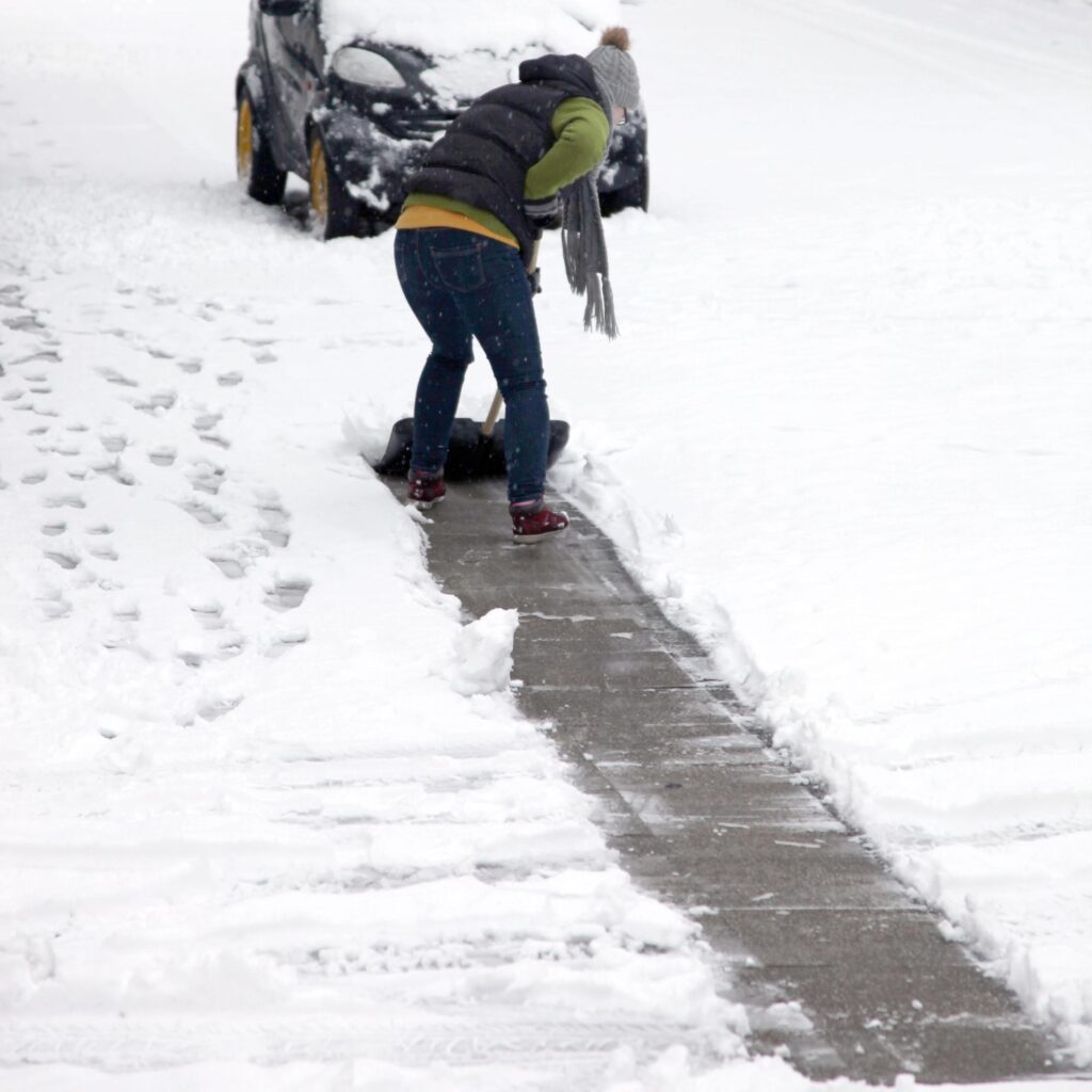 person shoveling snow off a walkway